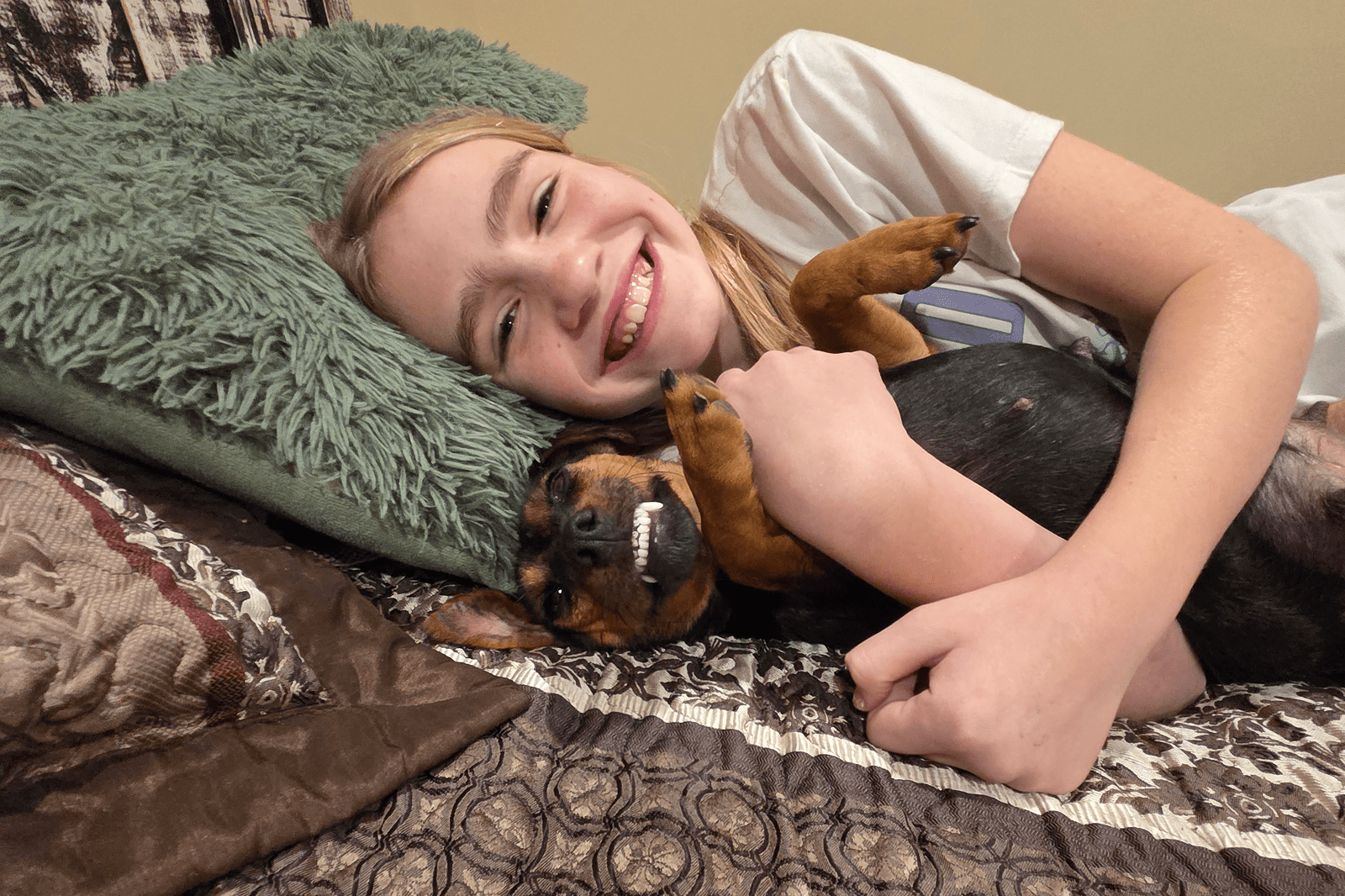 Smiling girl hugging small dog showing teeth