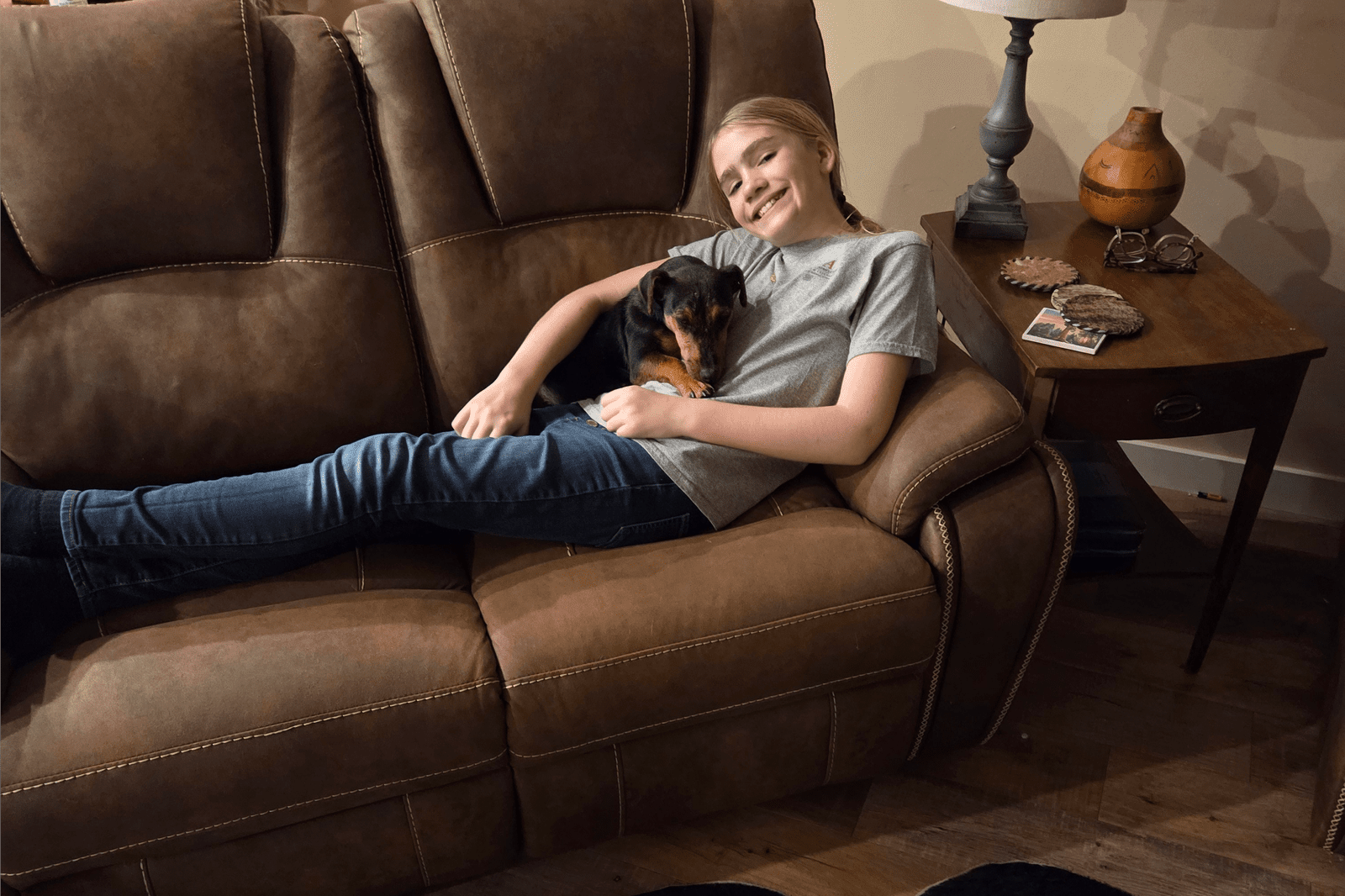 Smiling person cuddling small dog on couch