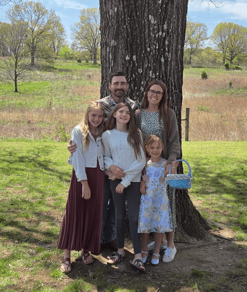 Family of five posing by a tree